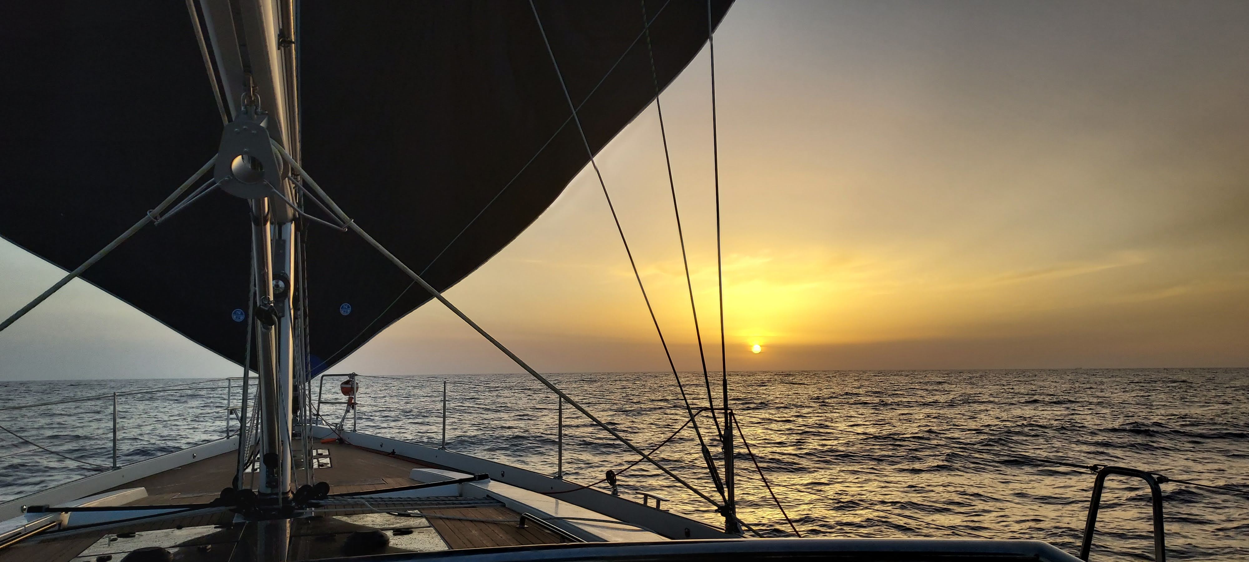 Sailing at sunset, view from the bow with sails up